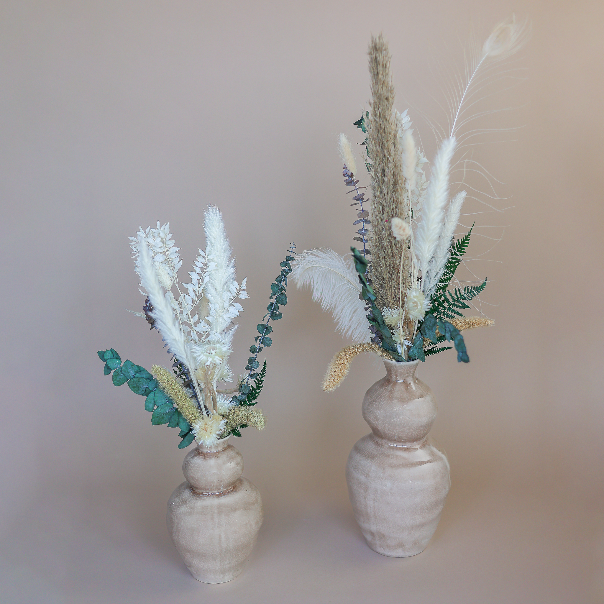 Zwei Trockenblumensträuße in Naturtönen in Vasen.