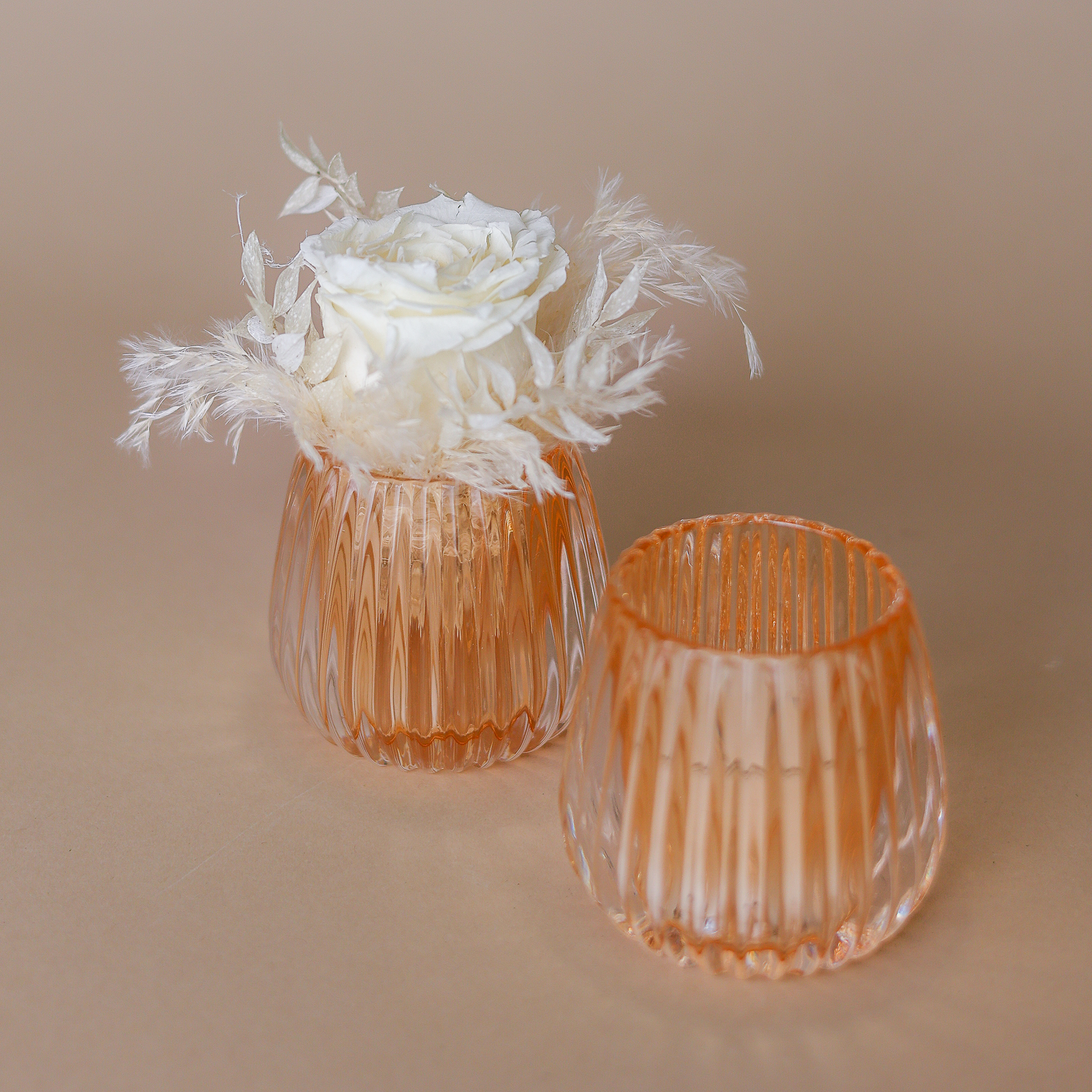 Honigfarbenes Windlicht mit einer natürlichen, stabilisierten Rose in weiß und passendem Beiwerk dekoriert.