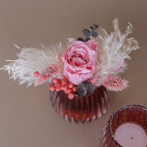 Roséfarbenes Windlicht mit einer natürlichen, stabilisierten Rose in rosé und passendem Beiwerk dekoriert.